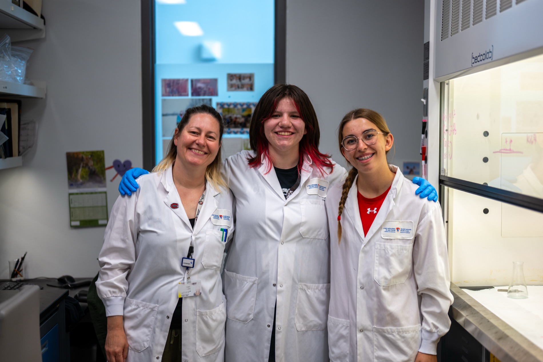 Two Kirkness Scholars and their mentor smiling in lab coats in a McGill research lab