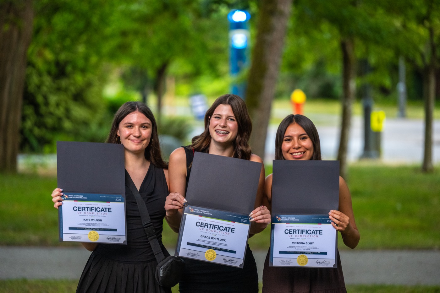 Three Kirkness Scholars holding their program certificates on campus