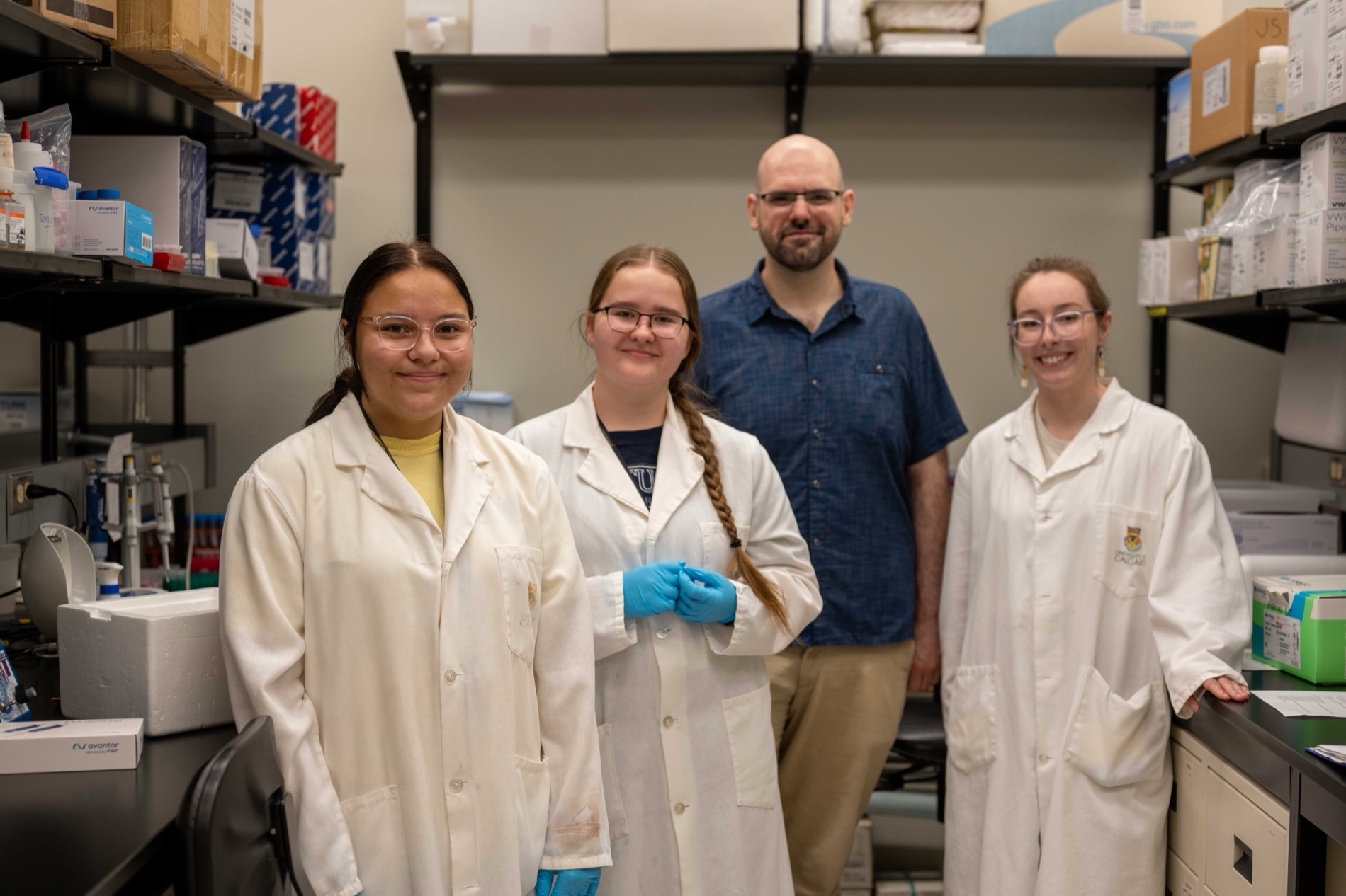Students in lab coats with their mentor in a University of Saskatchewan research lab