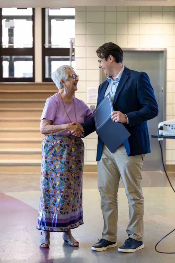 Dr. Verna J. Kirkness shaking hands with a Kirkness Scholar receiving his certificate