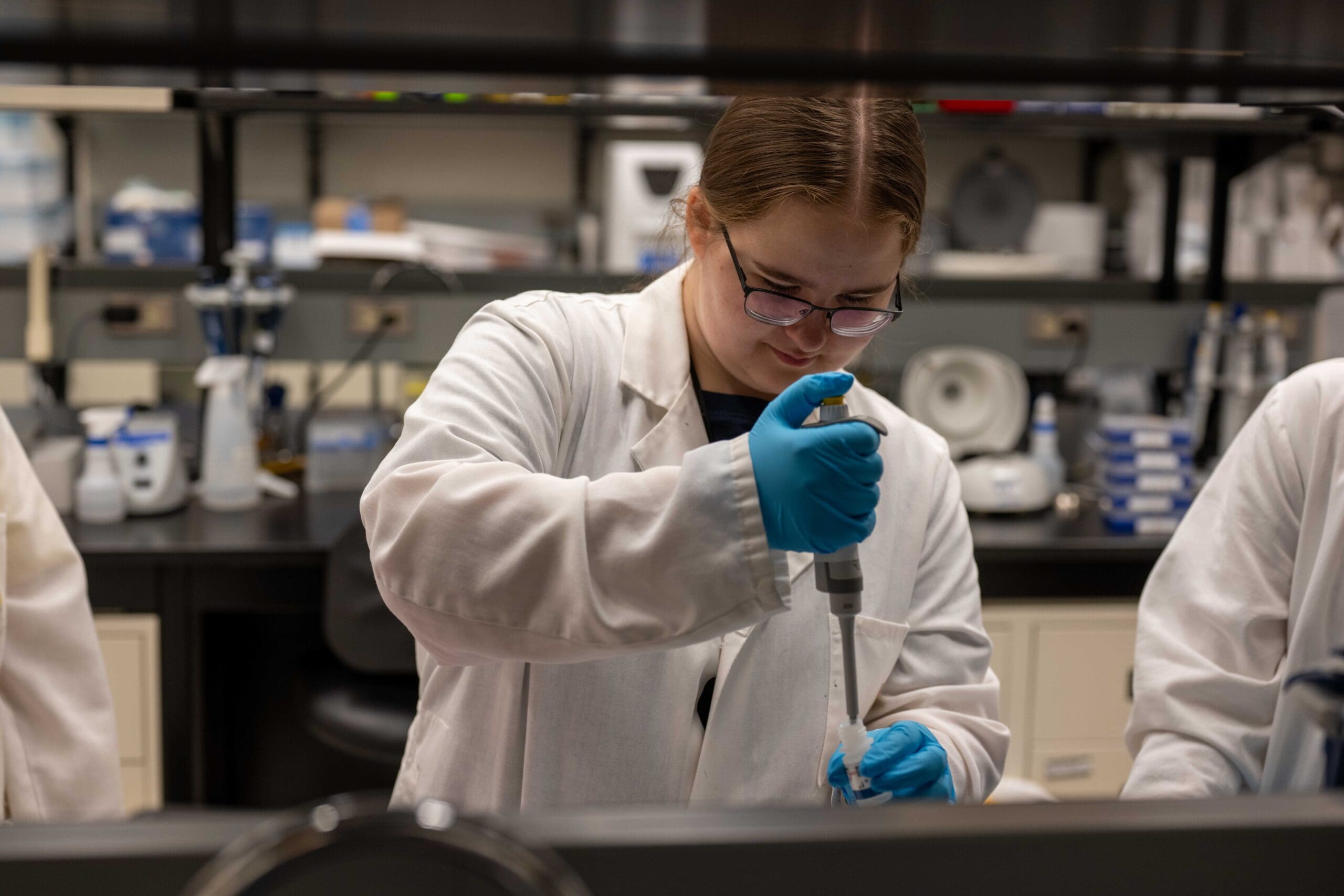 A Kirkness Scholar carefully using a pipette in a university research lab